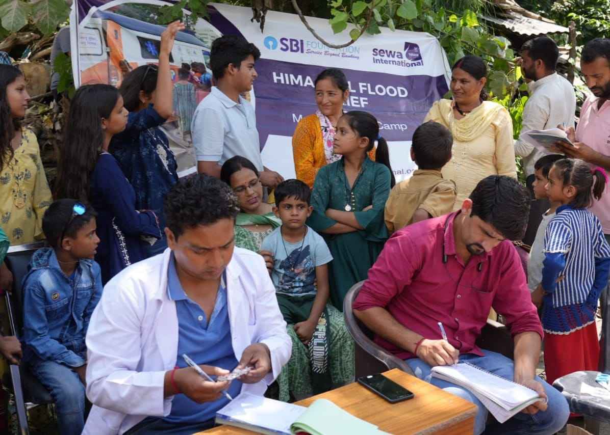 A doctor and a volunteer examining and registering villagers at a Sewa Himalaya flood-relief medical camp